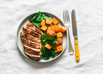 Roasted chicken breast, pumpkin and spinach - a delicious healthy lunch on a light background, top view