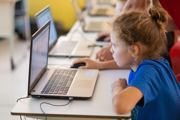 School children using computers in classroom at school.Interracial primary classroom learning to...