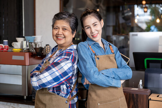 Lifestyle Asian elderly, healthy 60s mother, senior, pensioner, female standing with young barista waitress wearing apron uniform open cafe restaurant small business shop entrepreneur after retirement - Powered by Adobe