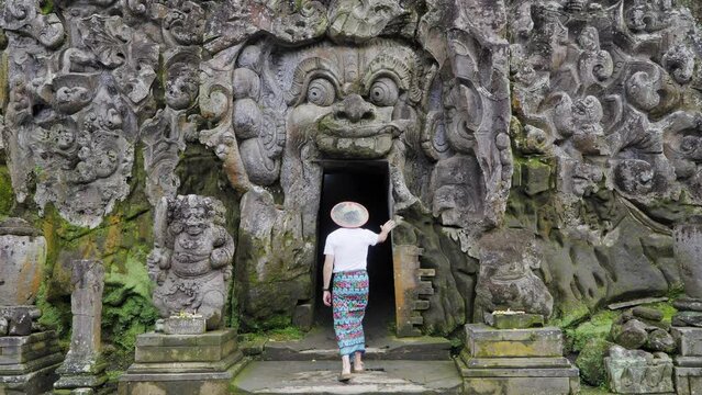 Journey into Mystery: Male Tourist dressed in traditional Balinese Sarong Explores Goa Gajah Elephant Cave, one of the holiest temples in Ubud, Bali. 4K Footage: Ideal for Spiritual and travel videos
