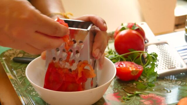 Female hands grated tomato in container for paella.