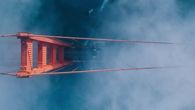 Aerial of red Golden Gate bridge. Busy road of red bridge over deep blue Pacific Ocean waters. Top down fog drifting around industrial architecture construction in San Francisco bay, California USA 4K
