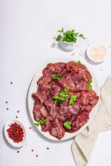 Raw chicken liver on stone background. Fresh ingredients ready for cooking, parsley, red pepper