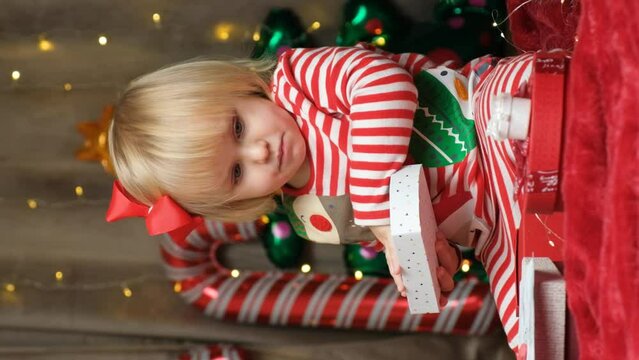 Cute two-year-old girl playing with Christmas gifts.