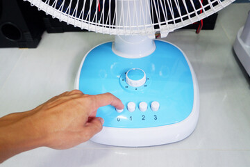 Man's hand pressing a fan button and turning the timer.