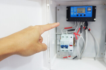 Man's hand showing the installation of a solar charger and circuit breaker in a cabinet for a solar cell system.