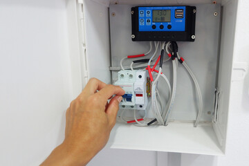 Man's hand showing the installation of a solar charger and circuit breaker in a cabinet for a solar...