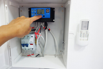Man's hand showing the installation of a solar charger and circuit breaker in a cabinet for a solar...