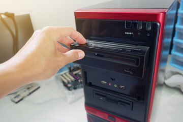 Man's hand inserting CD-ROM into computer case
