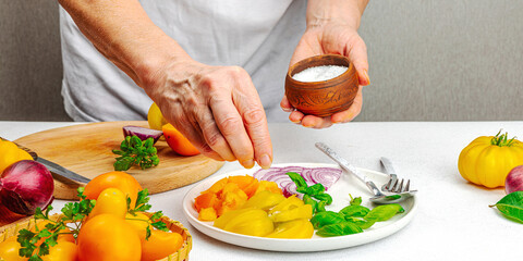A woman is preparing a tomato salad. Ripe vegetables, herbs, aromatic spices, olive oil
