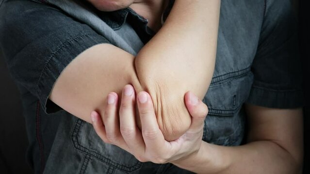 A man has pain in his elbow and tendon muscles and he relieves the pain with a massage. Health and healing concept