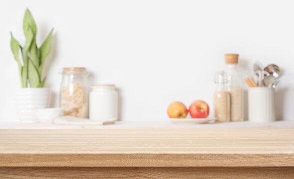 Wooden table background for product display montage with blurred kitchen utensils and food ingredients