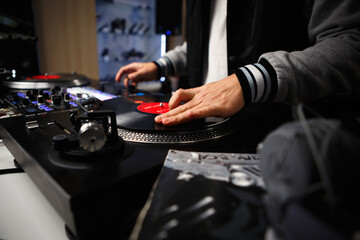 Cool hip hop DJ scratching a record. Disc jokey mixing musical tracks with turntables and audio mixer device
