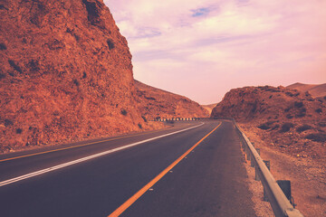 Driving a car on mountain road in desert. View of sandstone mountains through windscreen. Israel