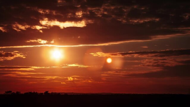 Amazing sunset in orange sky with dark dramatic clouds, Timelapse. 4K. Bright sun setting down above the horizon. Colorful sunset, epic clouds. Vibrant color. Time-lapse. Sundown, cloudscape