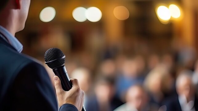 The auctioneer conducts the auction with a microphone on blurred background.
