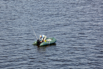 Mature man fishing on the lake from rubber inflatable boat. Fishing on the river. Natural river background