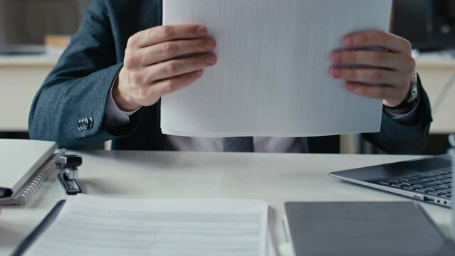 Cropped shot of unrecognizable executive manager working on laptop and then stapling documents with stapler in office