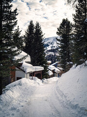 Fototapeta na wymiar Empty snow covered street in a ski resort village with chalets in Carinthia