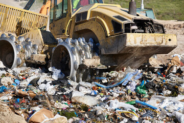 Fototapeta premium Heavy machinery shredding garbage in an open air landfill. Pollution