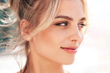 Fototapeta premium Closeup portrait of young beautiful smiling woman. Sexy carefree model posing on the street background at sunset. Positive blond female. Cheerful and happy. Outdoors at sunny day