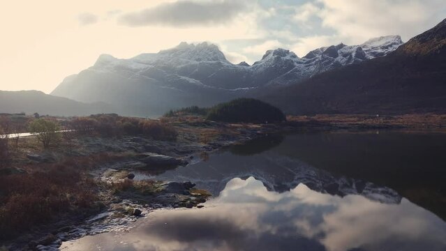 Aerial view low over a pond with mountain background, gloomy day in Lofoten, Norway
