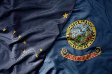 big waving colorful national flag of idaho state and flag of alaska state .
