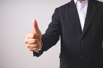 A businessman in a black suit stands and raises his hands.