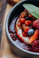 Tasty baked Camembert brie cheese with cranberry sauce and berries in restaurant. Gourmet appetizer