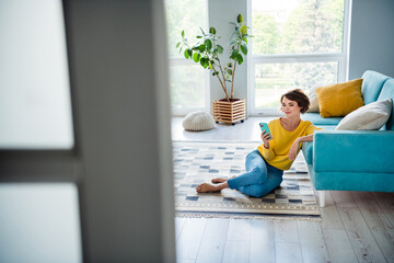 Photo of pretty positive cute girl wear trendy clothes sitting on carpet use modern phone writing...