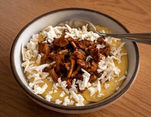 Tasty banosh served with brynza and mushrooms in bowl on table, top view. Traditional Ukrainian dish