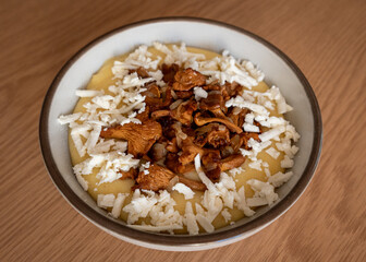 Tasty banosh served with brynza and mushrooms in bowl on table, top view. Traditional Ukrainian dish