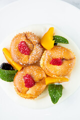 muffins with peach, raspberry, black berry and mint covered with powdered sugar, side view
