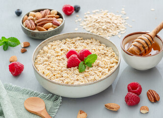 Bowl of porridge or oatmeal with fruits, nuts and honey. Breakfast cooking.