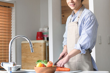 キッチンで料理するエプロン姿の若いアジア人の男性
