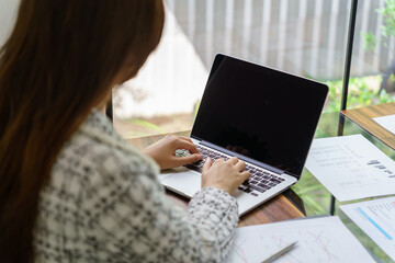 Woman Working by using laptop blank screen computer . Hands typing on a keyboard.technology e-commerce concept