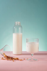 Transparent bottle and cup filled with soy milk decorated with many soybeans over blue background. Soy milk is packed with plant compounds