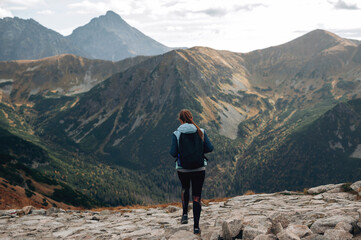 Back view of young woman with backpack standing on top of Tatra mountains 