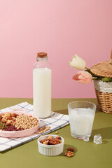 Milk filled inside a unbranded bottle and a cup with ices. Many types of organic nuts and beans are displayed. Nuts and beans are largely composed of fats
