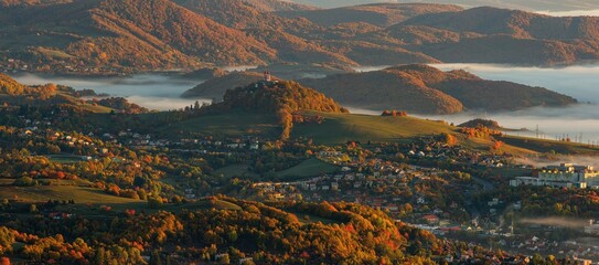 Beautiful autumn landscape of a church on a hill,  autumn fog in the valleys. Idyllic scenery from a bird's eye view of the picturesque town of Banska Stiavnica