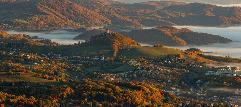 Beautiful autumn landscape of a church on a hill,  autumn fog in the valleys. Idyllic scenery from a bird's eye view of the picturesque town of Banska Stiavnica