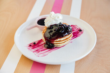 Raspberry pancake with whipped cream served in a cafe environment.
