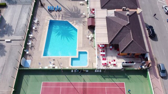 Drone aerial shot following tennis court, swimming pool and park at Cabo Cervera, Torrevieja