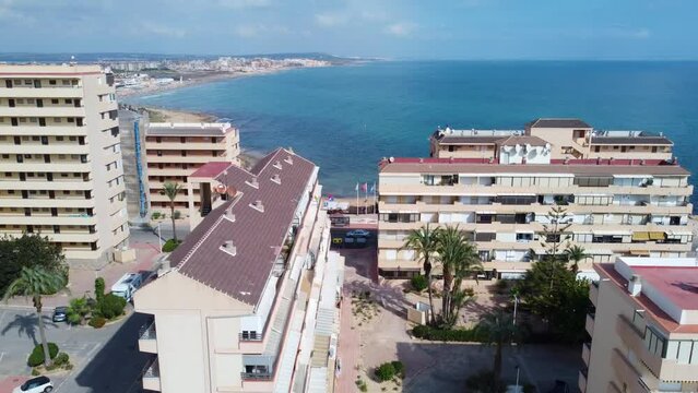 Drone aerial shot between apartment buildings at Cabo Cervera showing the sea and popular beach at La Mata, Torrevieja