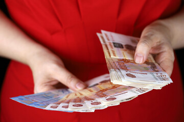 Russian rubles in female hands, cash pay, salary, inflation or savings concept. Woman in red dress...