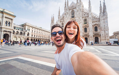 Happy couple taking selfie in front of Duomo cathedral in Milan, Lombardia - Two tourists having fun on romantic summer vacation in Italy - Holidays and traveling lifestyle concept - obrazy, fototapety, plakaty