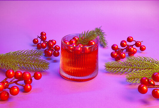 Yuletide Celebration in Crimson and Lavender: A Cocktail Toast with Ruby Red Beverage, Holly Berries, and Pine Foliage on a Festive Purple Backdrop
