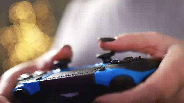 Wireless joystick in female hands with black manicure.