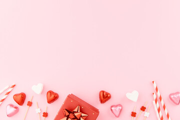Red gift boxes with ribbons, heart shaped candies, marshmallows and paper heart decorations on pink...