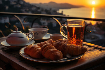 cup of coffee and french croissant on table, balcony with view of beautiful landscape, still life, sea and mountains, resort town, sunset